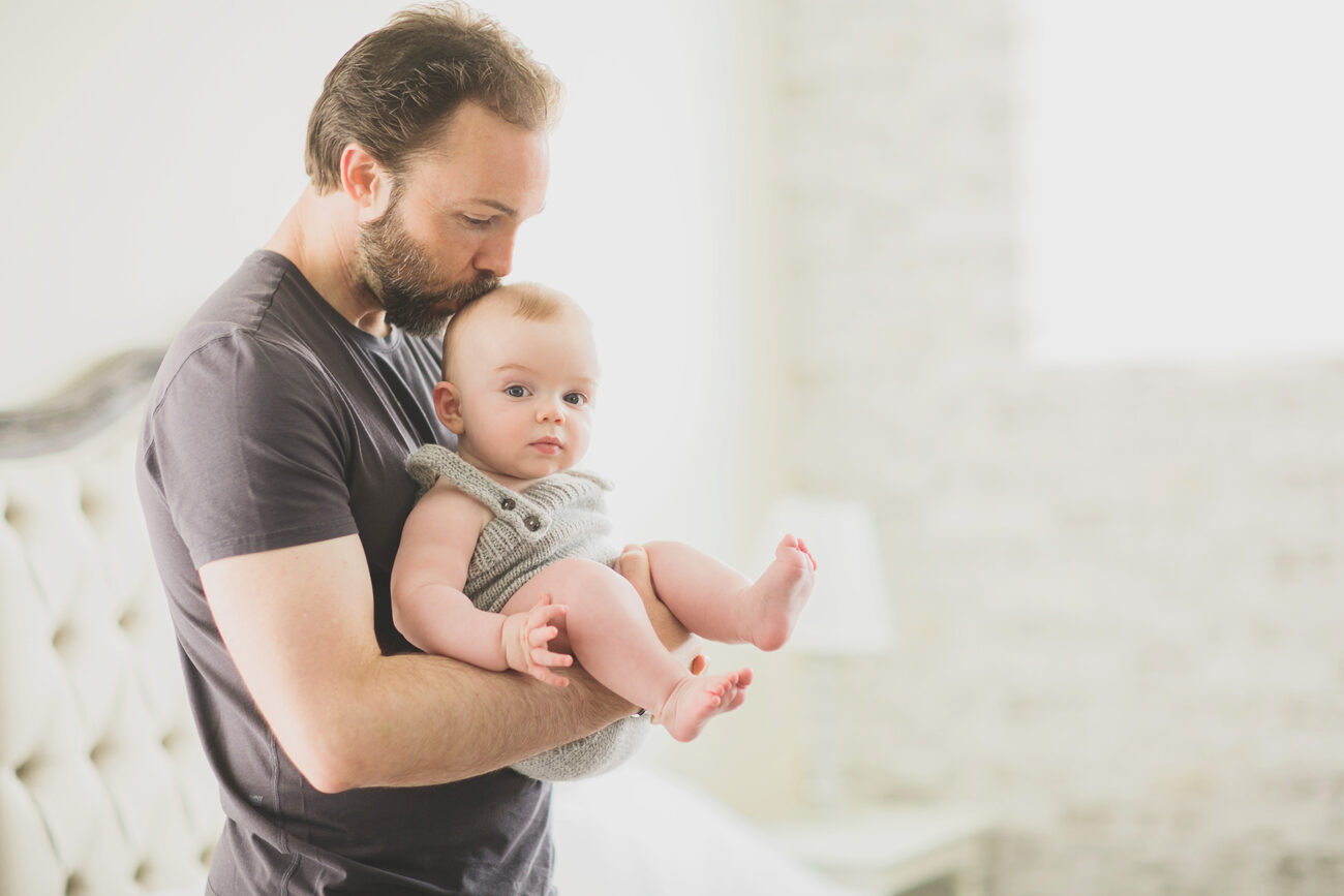 Father kissing baby’s head during in-home Boise baby photography session