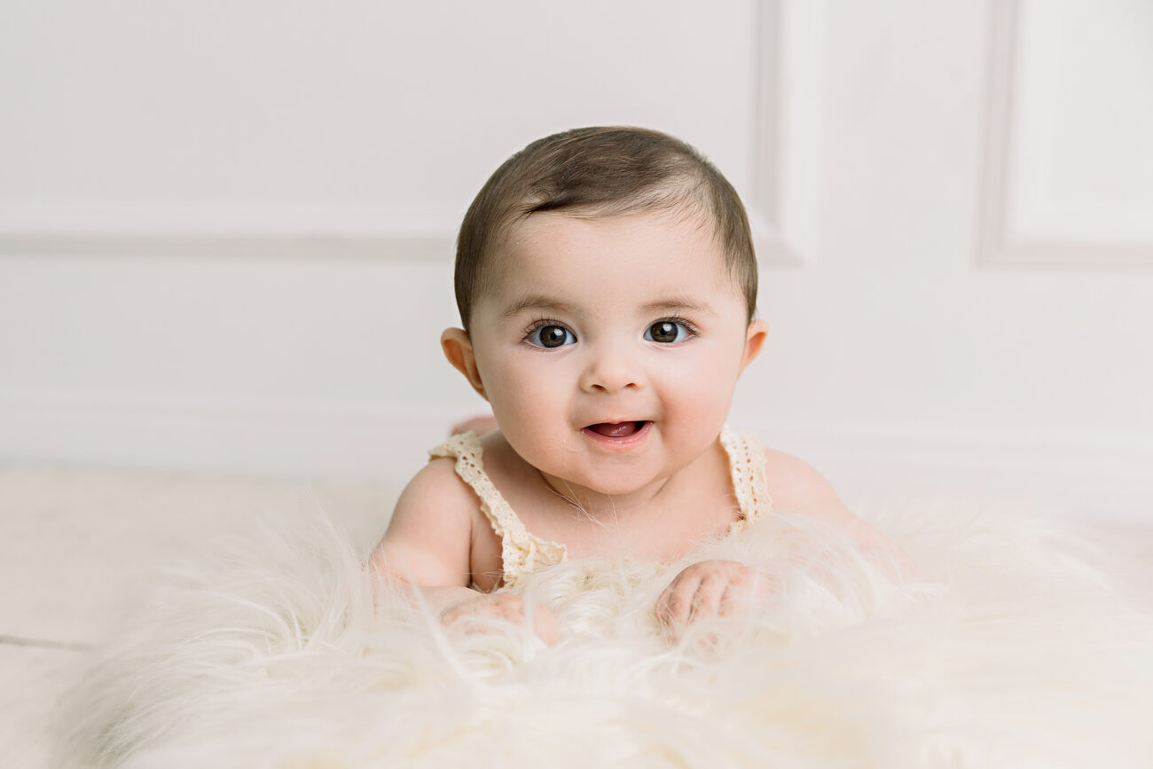 Baby sitter session, laughing brown-eyed baby on cream fur, Boise baby photographer