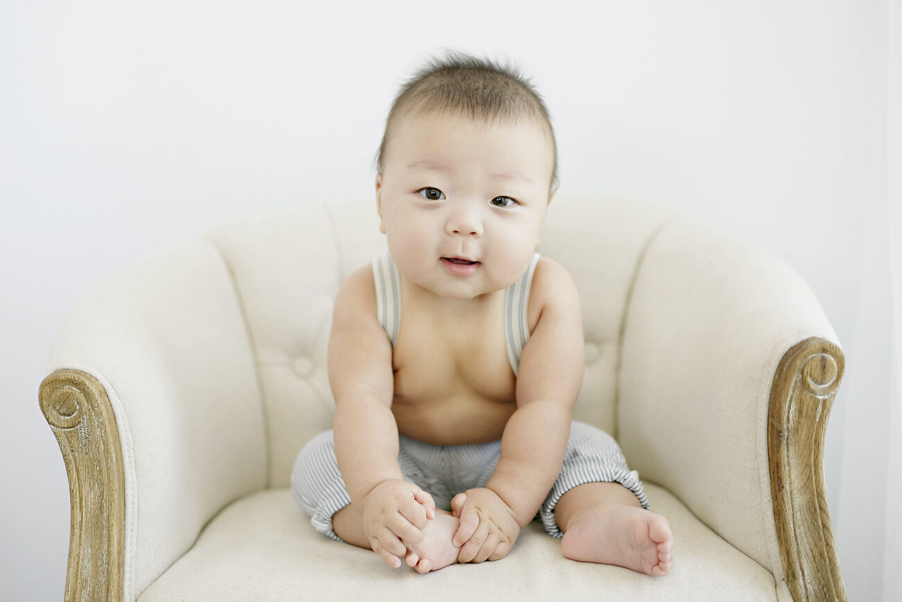 Baby boy sitting on cream linen armchair, timeless Boise baby photos