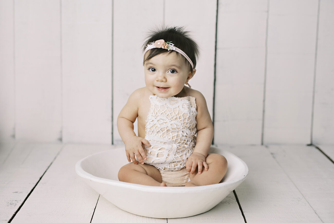 Happy baby girl in lace romper sitting in white bowl, Boise baby photos
